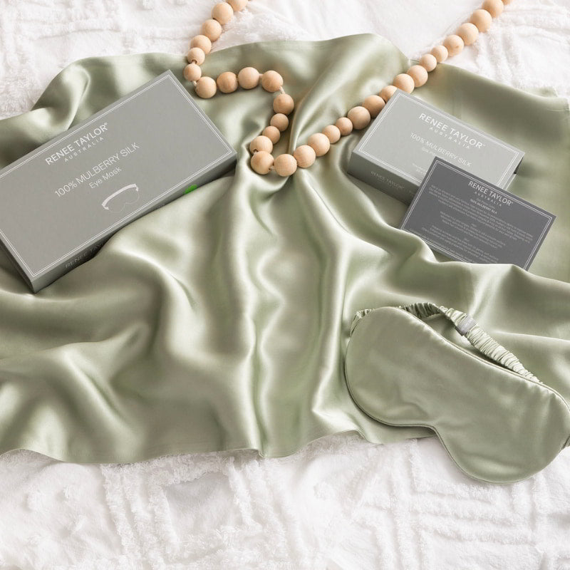 alt="A green satin standard pillowcase, and eye mask made from 100% pure mulberry silk."