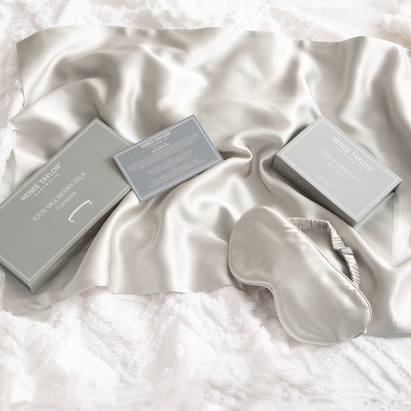 alt="A silver satin standard pillowcase, and eye mask made from 100% pure mulberry silk."