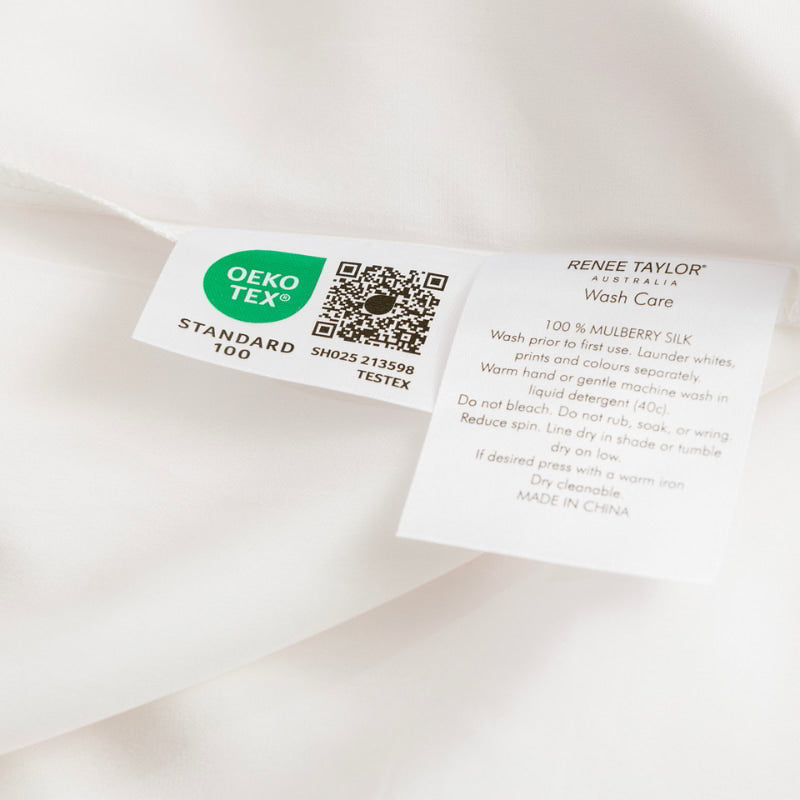 alt="A white sheet with a green label made from 100% pure mulberry silk. Softly padded with 6 layers, it glides gently across your skin, preventing wrinkles and creasing."