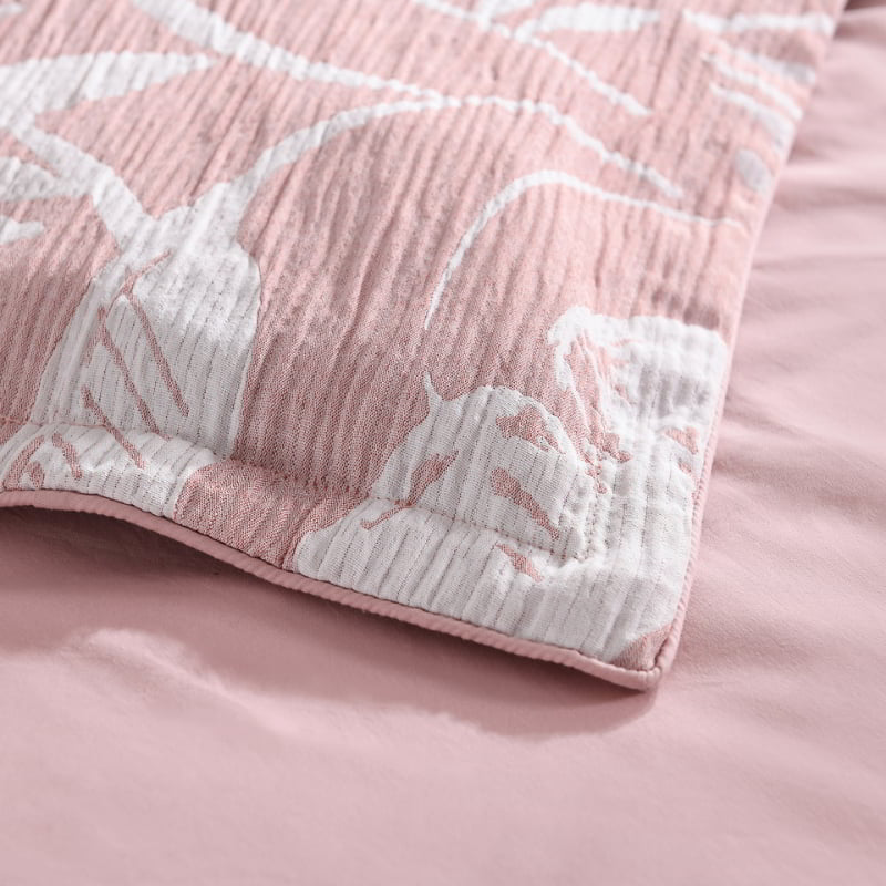alt="Zoom in details of a shade of pink european pillowcase featuring intricate island themes with swaying palm trees in tropical rainforest"