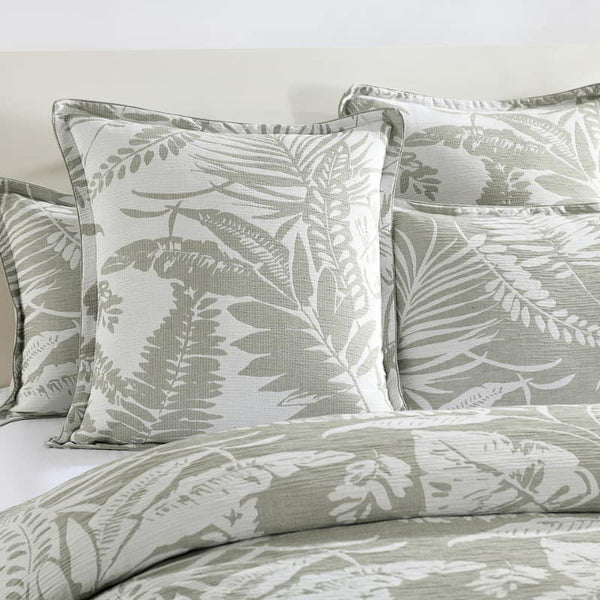 alt="Showcasing a shade of sage green european pillowcase featuring intricate island themes with swaying palm trees in tropical rainforest."