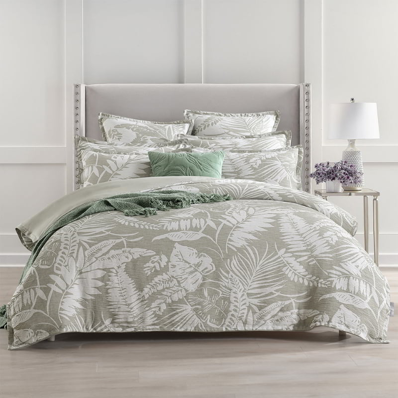 alt="A shade of sage green european pillowcase and quilt cover featuring intricate island themes with swaying palm trees in tropical rainforest in a luxurious bedroom."