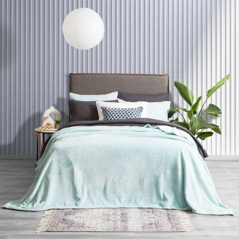 Lavish bed adorned with a pristine blue ultra soft velvet blanket and generously oversized.