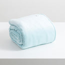 A sumptuous, generously-sized, ultra-soft  blue velvet blanket, elegantly folded on a pristine white surface.
