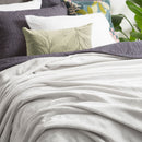 An indulgent bed, generously proportioned, adorned with a pristine  silver line clolour velvet blanket and plush pillows