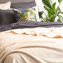 An indulgent bed, generously proportioned, adorned with a pristine sand clolour velvet blanket and plush pillows