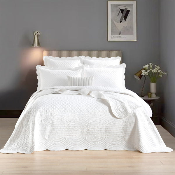 alt="Showcasing a white coverlet set with a nod to French quilting tradition and decorative details like scallop edges"