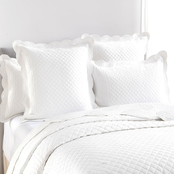 alt="Showcasing a tone of white european pillowcase with a nod to French quilting tradition and decorative details like scallop edges in a cosy bedroom."