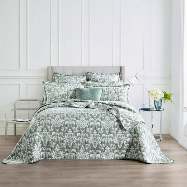 alt="Showcasing elegant coverlet boasting a timeless jade and white damask pattern, highlighted by sharp, straight piped edge detailing in a luxurious bedroom."