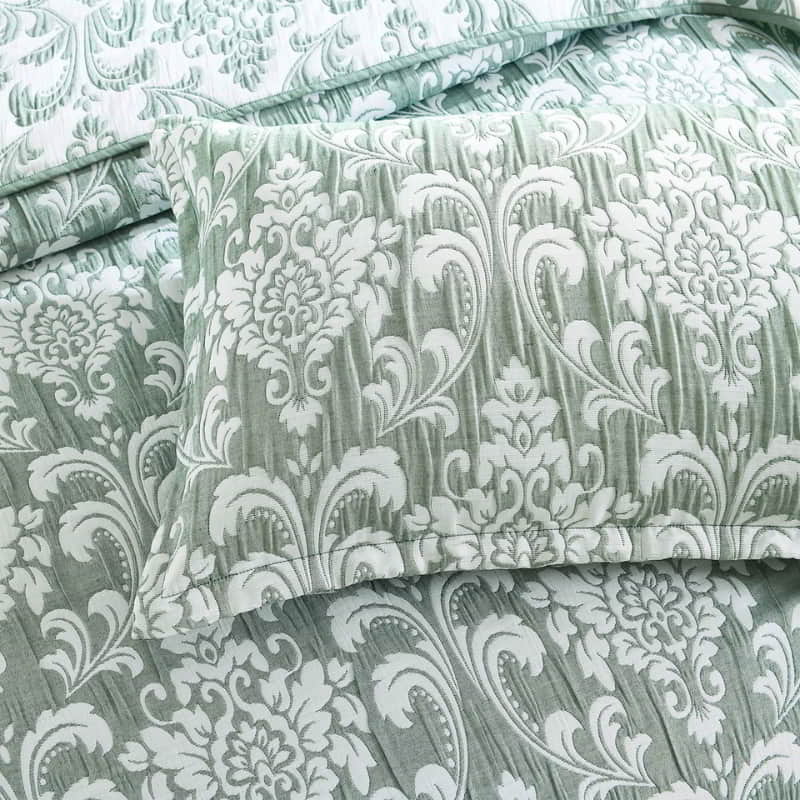alt="A green and white bed with an intricate textile pattern, featuring a timeless jade & white damask design and elegant detailing. Perfect for all seasons."