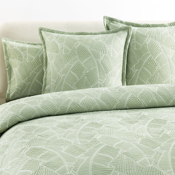 Sage green European pillowcase with jacquard banana leaf design on bed

