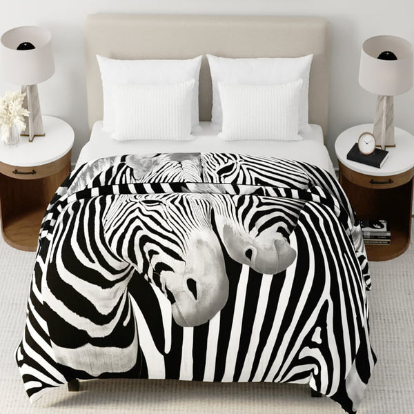 Zebra print mink blanket styled on a bed with white pillows and neutral decor