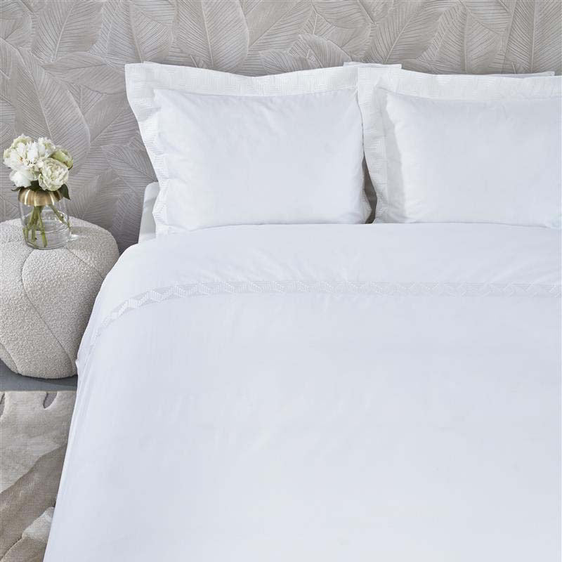 alt="Close-up look of a sophisticated white quilt cover set featuring a narrow horizontal band with embroidered geometric pattern"