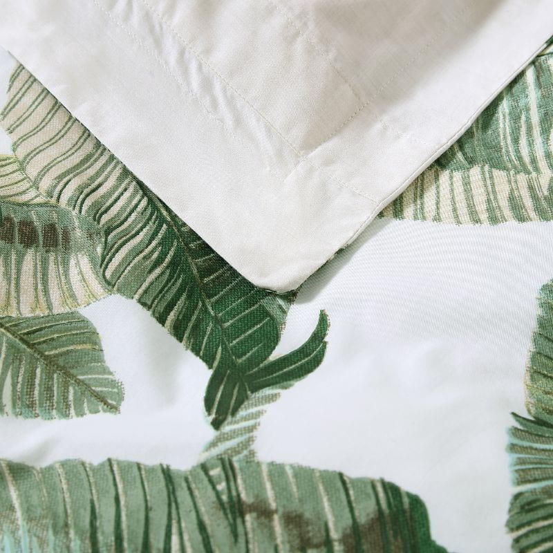 Close-up details of a luxurious tropical print bedding set with palm leaves, perfect for a peaceful and comfortable siesta. 