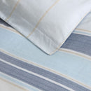 Close up details of a serene bedroom with a soft blue striped quilt cover set, creating a calming atmosphere for sweet dreams.