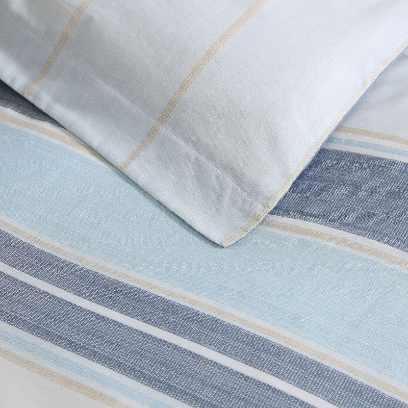 Close up details of a serene bedroom with a soft blue striped quilt cover set, creating a calming atmosphere for sweet dreams.