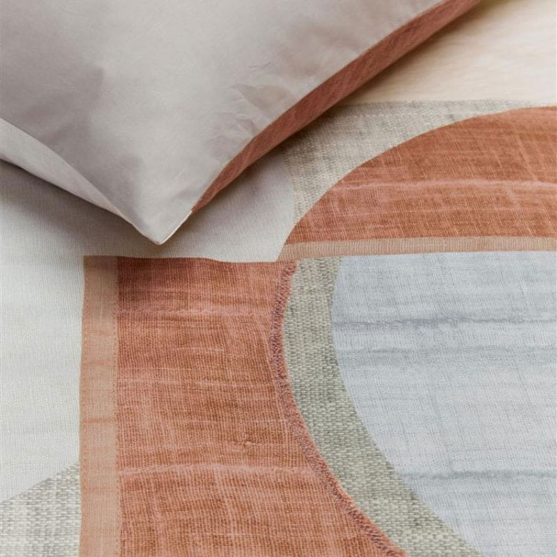 alt="Close-up look of a high-quality cotton quilt cover with a modern graphic print in natural and terracotta colours. The printed linen texture on the background adds depth to the design, while the reverse side is a solid sand colour."