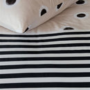 alt="Close-up look of a dotted and striped quilt cover with hand-painted black and white dots on a cream background on the top side and horizontal black and white stripes on the underside"