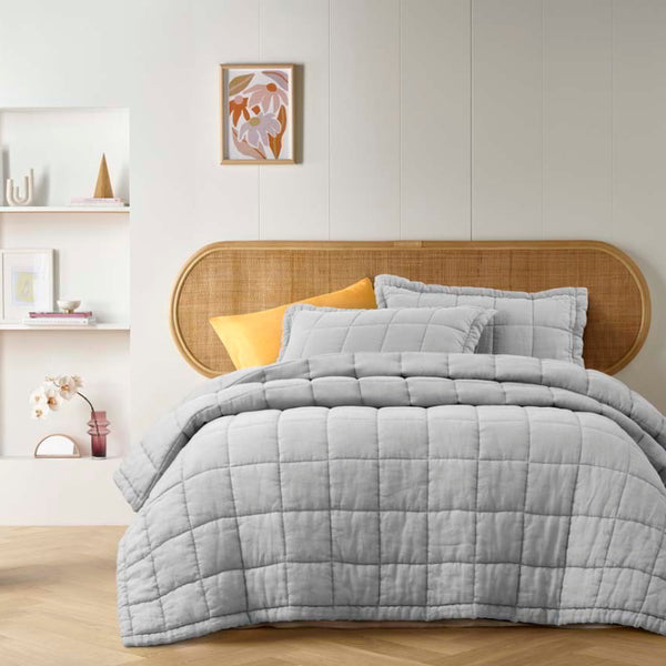 alt="A french linen coverlet set with 2 quilted pillowcases in a cosy bedroom."