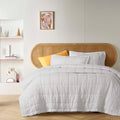 alt="White french linen coverlet set with 2 quilted pillowcases for luxurious comfort and style in a cosy bedroom."