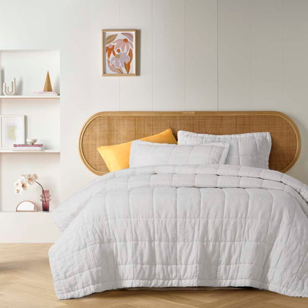 alt="White french linen coverlet set with 2 quilted pillowcases for luxurious comfort and style in a cosy bedroom."