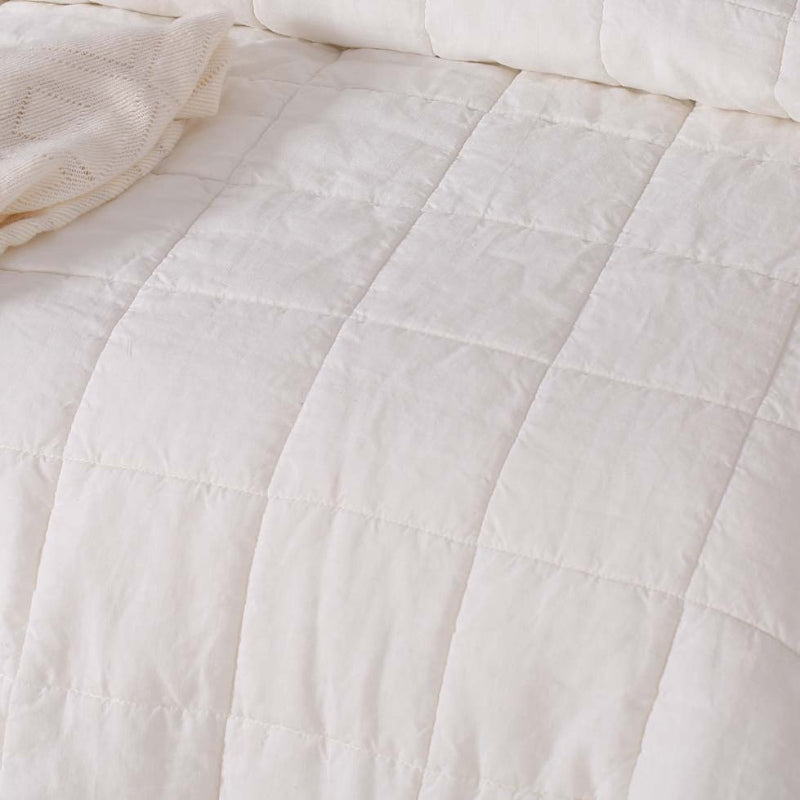 alt="Close up look of a white french linen coverlet set with 2 quilted pillowcases for luxurious comfort and style"