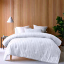 alt="A white comforter set featuring chenille stripes design on a cosy bedroom"