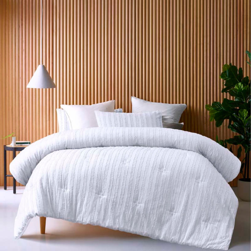 alt="A white comforter set featuring chenille stripes design on a cosy bedroom"