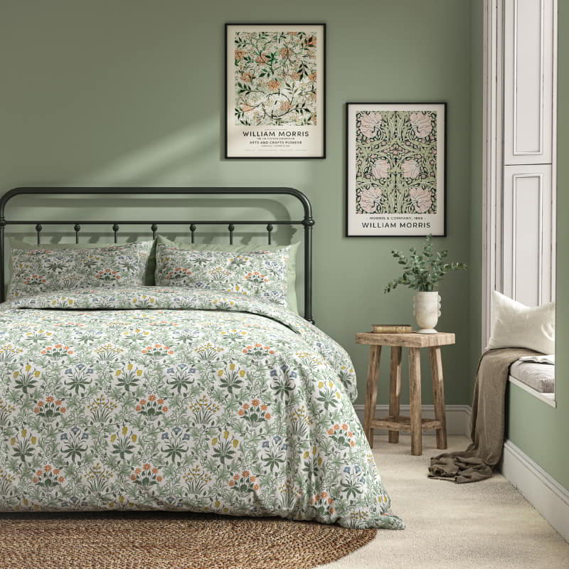 William Morris At Home Celadine Eau De Nil Quilt Cover Set with a soft heritage pattern in green tones, styled in a bright, airy bedroom.