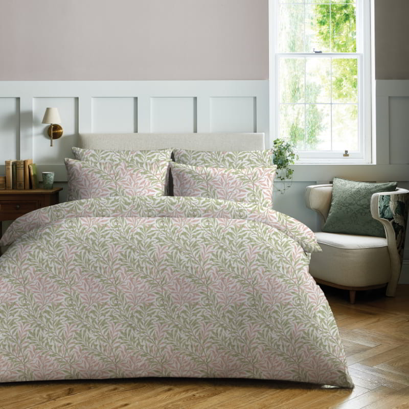 William Morris At Home Willow Bough Summer Quilt Cover Set featuring a delicate green leaf pattern on a crisp white background, styled in a sunlit bedroom.