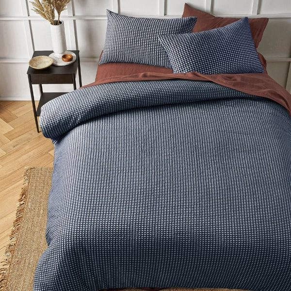 Navy waffle quilt cover set styled with matching pillowcases on a bed.