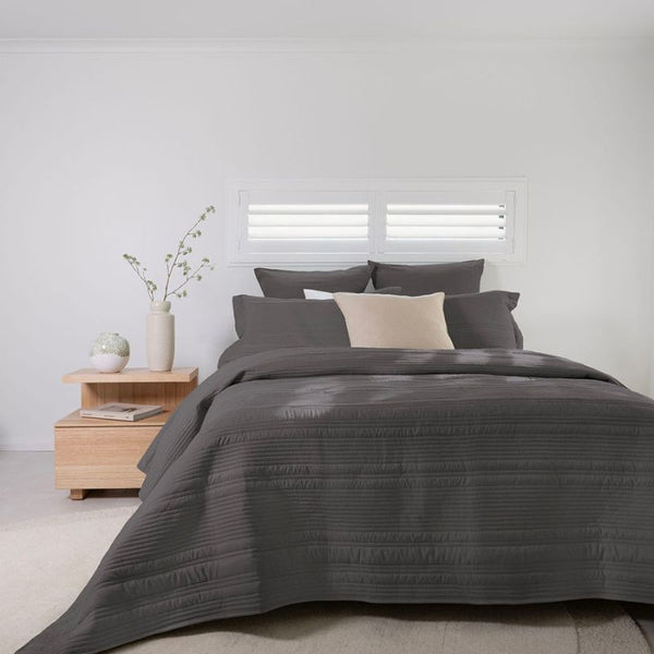 Lightweight dark grey coverlet set with soft texture and neutral cushions.