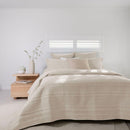 Soft neutral coverlet set paired with light cushions and timber bedside table.