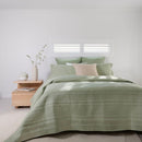 Lightweight sage coverlet set paired with neutral cushions on a timber bedside.