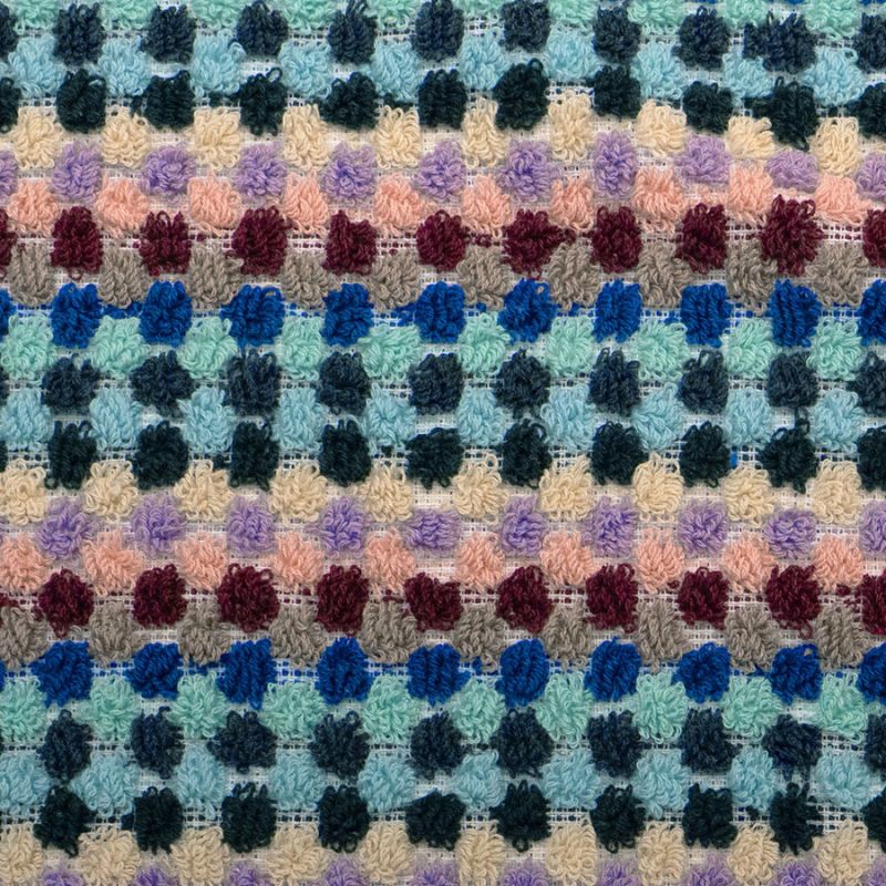 Close-up of textured pom pom weave in multi-coloured pattern.