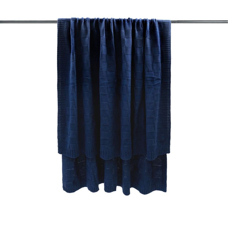 Close-up of the knitted texture and square pattern on the navy throw.