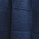 Close-up of the knitted texture and square pattern on the navy throw.