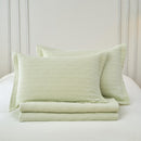 Lightweight cotton coverlet in soothing green draped neatly over a bed.
