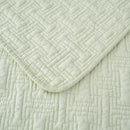 Lightweight cotton coverlet in soothing green draped neatly over a bed.