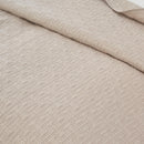 Soft neutral cotton throw with detailed stitching and bound edges.