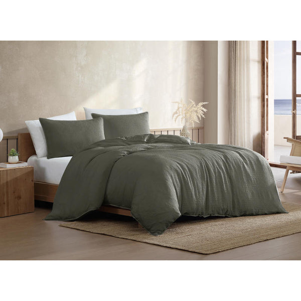 Textured green quilt cover set with matching pillowcases on wooden bed frame.