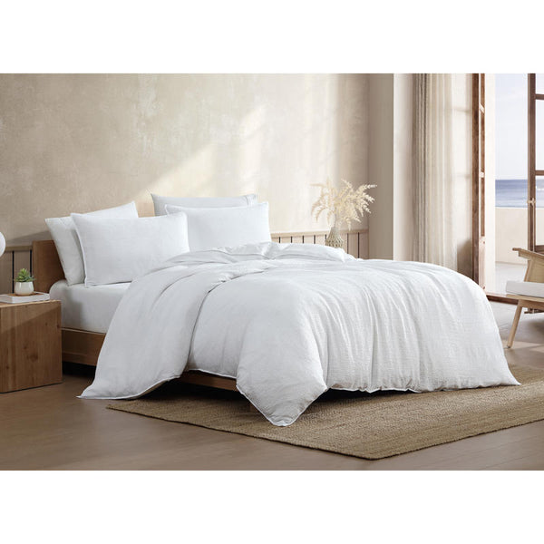 Textured white quilt cover set with matching pillowcases on timber bed frame.