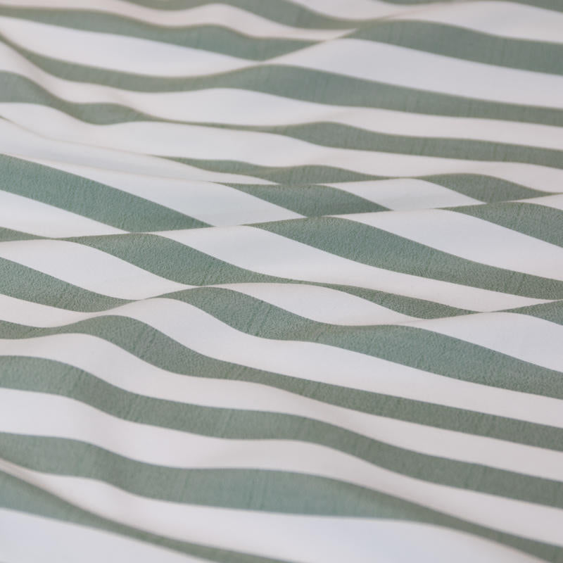 Coastal-inspired sage and white stripe quilt cover set in a relaxed modern bedroom.