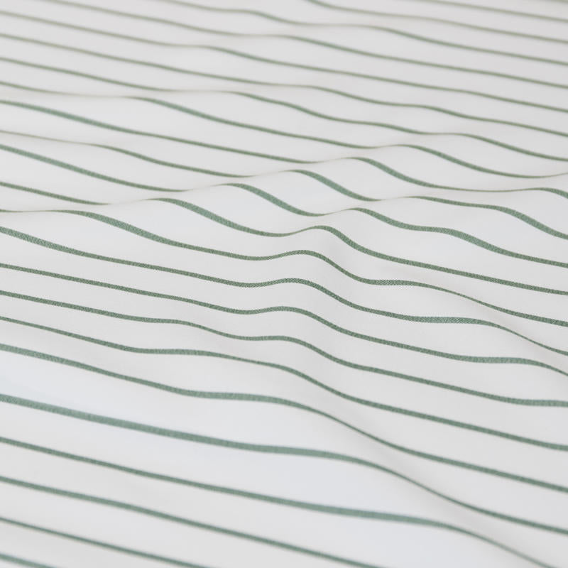 Coastal-inspired sage and white stripe quilt cover set in a relaxed modern bedroom.