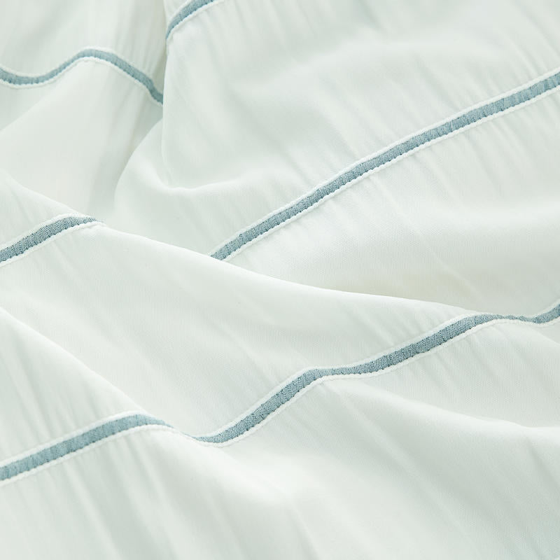 Light and airy blue striped quilt cover set on white bed.