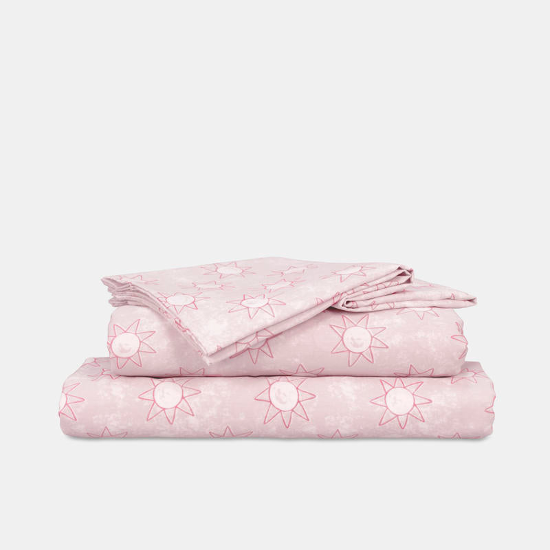 Close-up of playful pink sun print pattern on kids sheet set.
