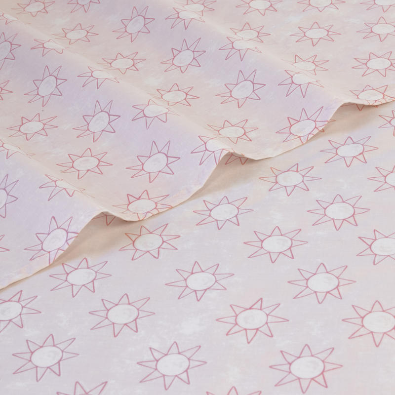Close-up of playful pink sun print pattern on kids sheet set.