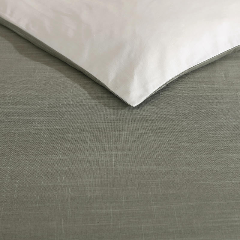 Modern interior with Kenneth Cole Nila Moss Green Quilt Cover Set on grey bedhead and neutral rug.