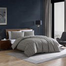 Kenneth Cole Sussex Khaki/Black Quilt Cover Set styled on bed with dark navy wall and wooden bedside table.