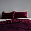 Red satin pillows on a bed against a gray wall
